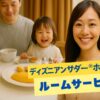 ディズニーアンバサダーホテルの客室で朝食を楽しむ家族の様子。テーブルにはミッキー型のパンケーキやオムレツが並ぶ。